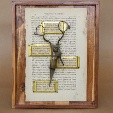 antique scissors and brass label plates on an antique book page